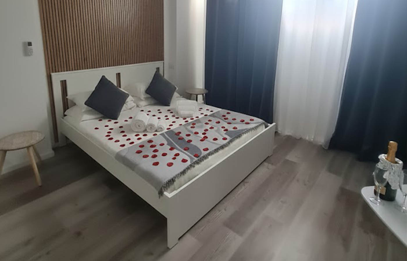 stanza mirto con petali di rosa sul letto e bottiglia di spumante omaggio